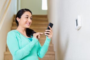 person-adjusting-thermostat-with-their-phone